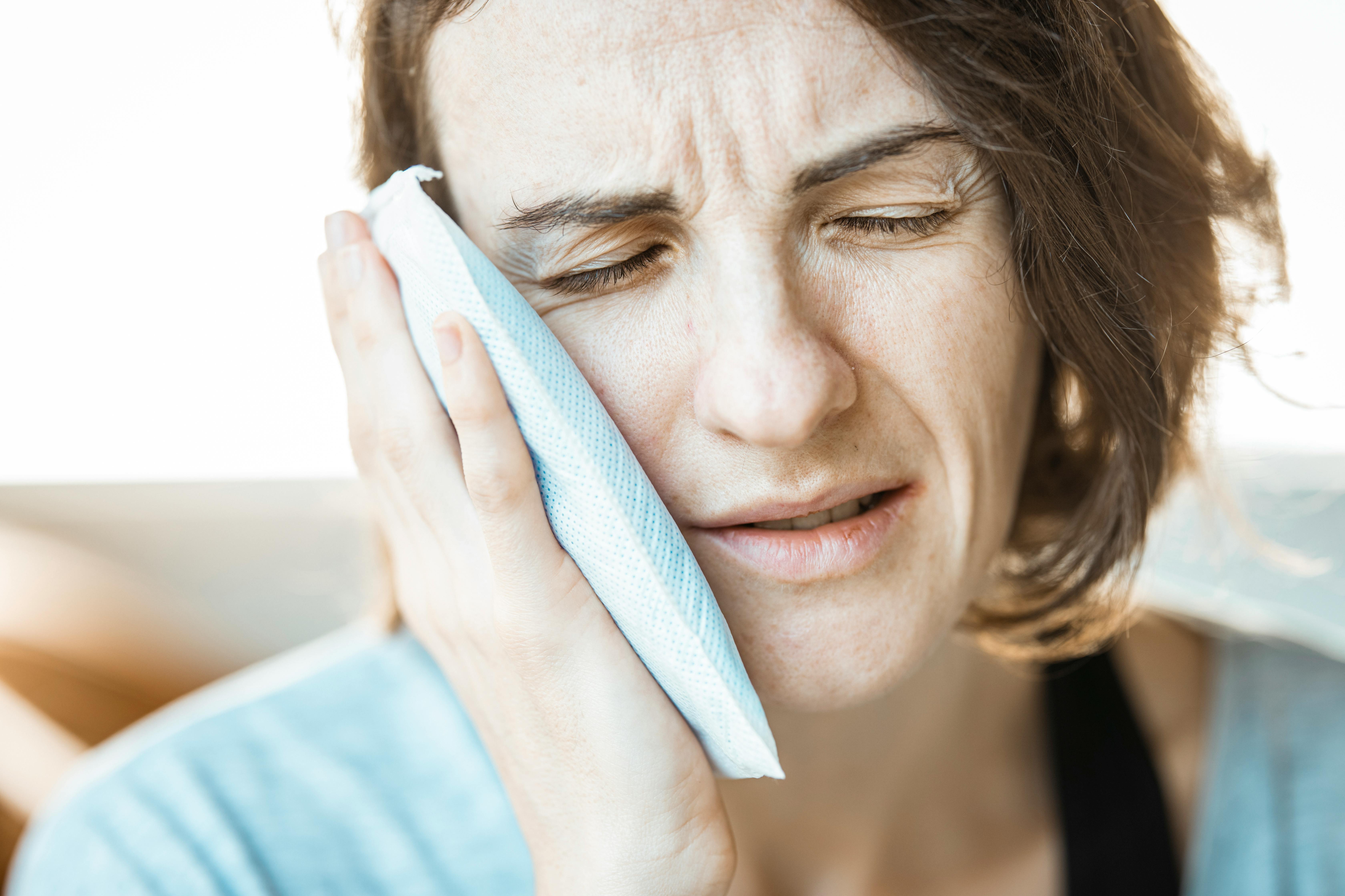 Woman holding a cold pack against her jaw due to TMJ pain
