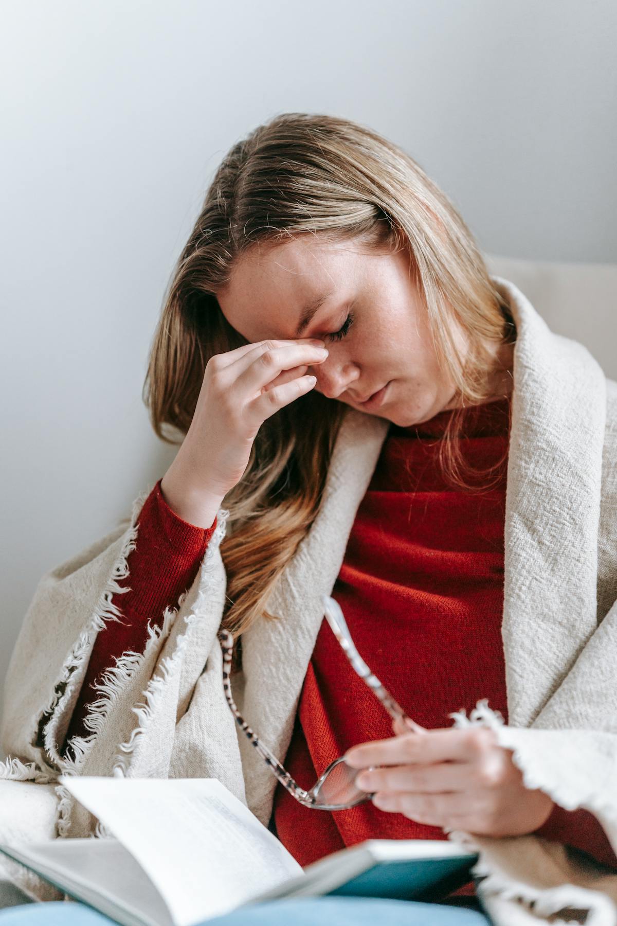 Woman with post-concussion headache and eye fatigue rubbing the bridge of her nose while reading